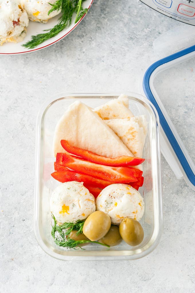 Meal prep container with ham & cheese egg white bites, vegetables, and pita.